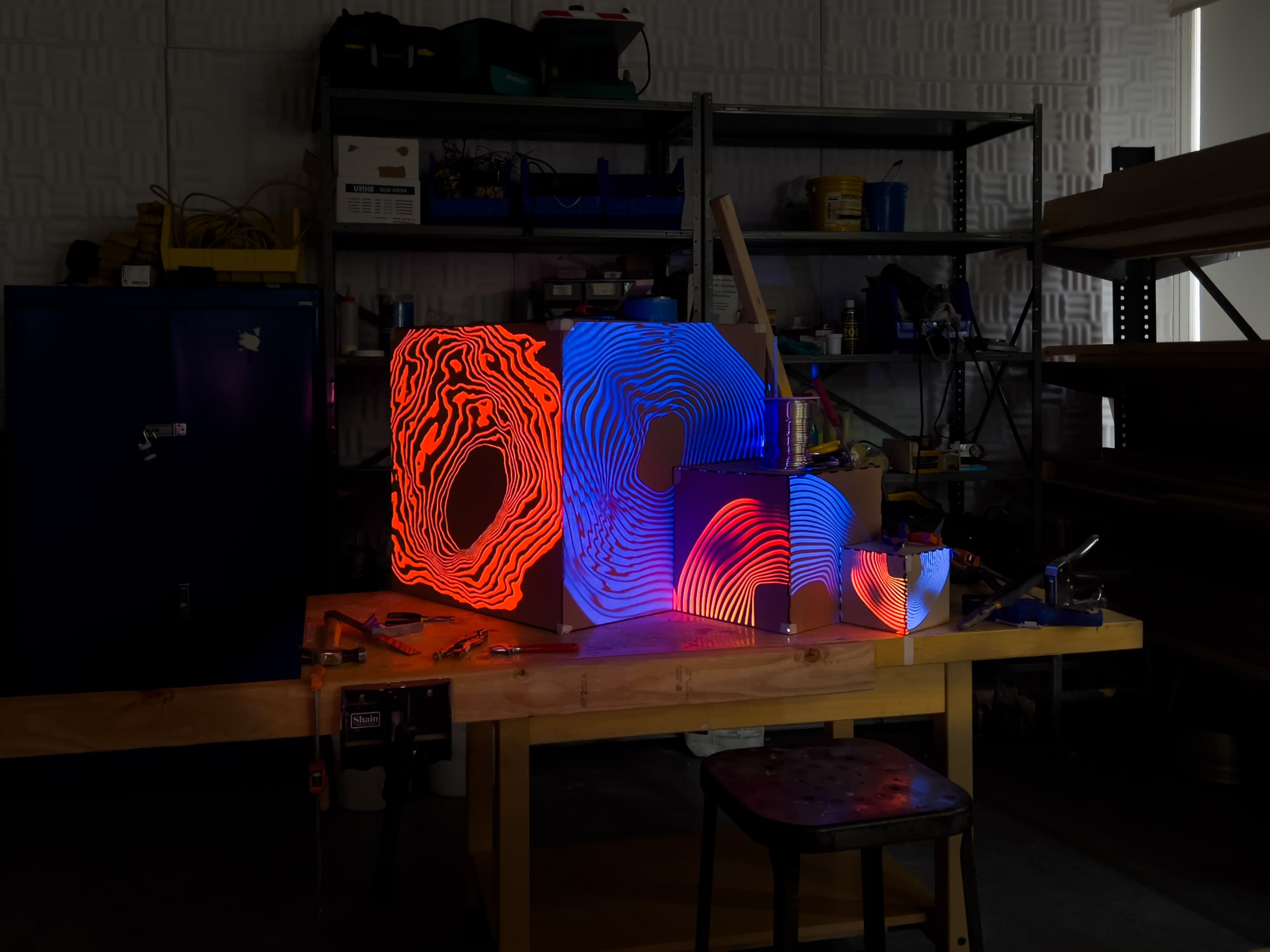 Projection mapping of a blue and orange pattern on the three cardboard cubes.